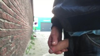 Boy piss outdoors while cars driving by