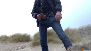 young man urinates in the dunes