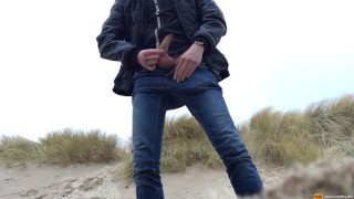 young man urinates in the dunes