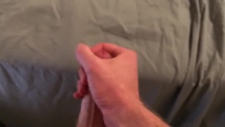 Guy jerks himself off, standing up then cums on the sheets