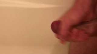 Guy pisses in the tub, then jerks himself off until he cums