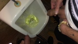 Boys piss and spit together at the urinal after some cocktails