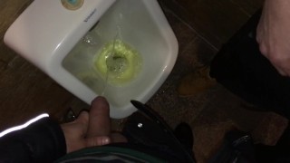 Boys piss and spit together at the urinal after some cocktails