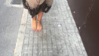 young female hippie is walking barefoot in public street