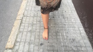 young female hippie is walking barefoot in public street