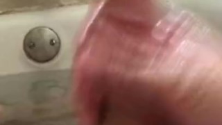 Stroking cock and hairy balls in bathtub with baby oil.
