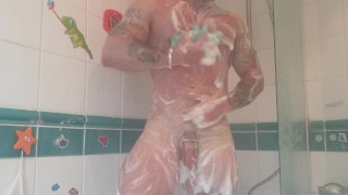 Muscular tattooed guy takes hot shower after the gym