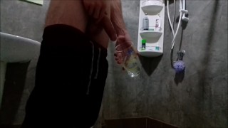 A guy in sweatpants pisses and cums in a glass for his friend, who then drinks it