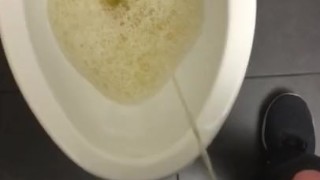 POV pissing into a toilet in a public bathroom and jerking off and cumming