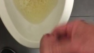 POV pissing into a toilet in a public bathroom and jerking off and cumming