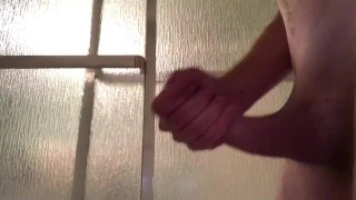 Guy strokes his cock, standing in the shower until he cums
