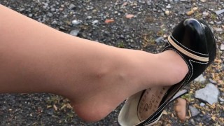 A girl walks in nature in black shoes and tights pantyhose under a skirt