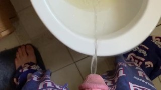 Male in pajamas peeing in toilet in bathroom