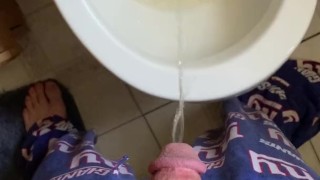 Male in pajamas peeing in toilet in bathroom