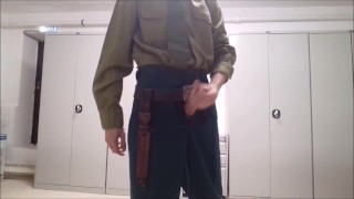 Russian soldier in a Soviet-era uniform masturbates his cock in the barracks in public