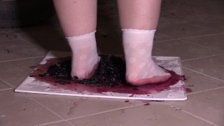 Plump legs in white socks mercilessly trample grapes. Crush fetish