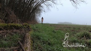 Naked stroll in a field by the forest on a foggy winter day