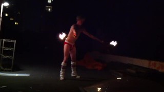 Blond guy spins fire on rooftop in socks and underwear