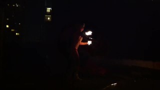 Blond guy spins fire on rooftop in socks and underwear