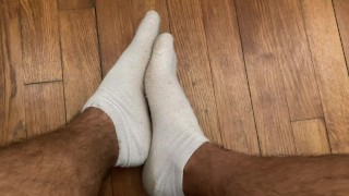 Étudiant joue avec ses pieds en chaussettes blanches