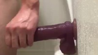 Riding dildo on wall of shower 