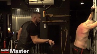 Slave on St Andrews Cross whipped with floggers turning his back from white to red. PREVIEW