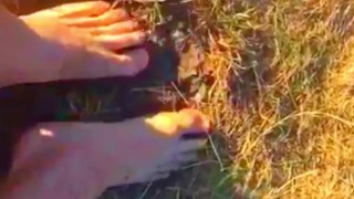 Solo guy rubbing feet in dirt outdoors