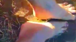 Solo guy rubbing feet in dirt outdoors