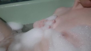 Girl playing with nipples in a bubble bath