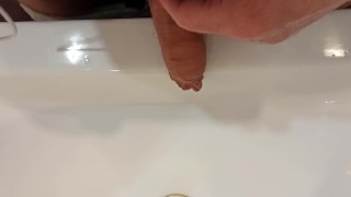 The boy is pissing into the washstand.