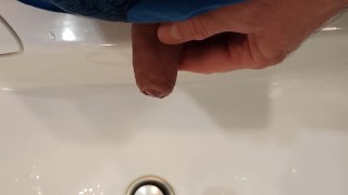 The boy is pissing into the washstand.