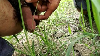 Boy pissing in grass field 
