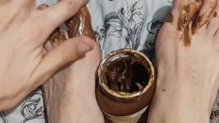 Skinny blonde covers his feet with Nutella and licks it off after