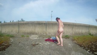 The girl undresses, walks and masturbates near the road by the lake