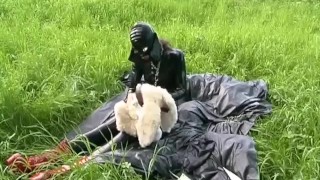 Rubber girl full in black latex catsuit and mask plays with herself outdoor in a meadow - Part 1