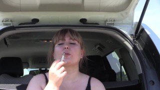 A cute bbw smokes in the street near the car