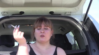 A cute bbw smokes in the street near the car