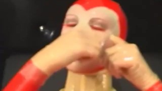 Sexy girl encased in red rubber catsuit loves medical games with mouth spreader and nipple clamps