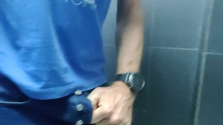 Locked in a chastity cage, man is pissing in a public toilet