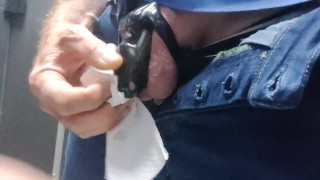 Locked in a chastity cage, man is pissing in a public toilet