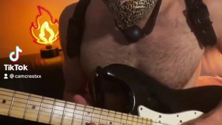 Guy with a ball gag plays guitar 