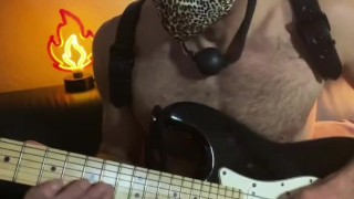 Guy with a ball gag plays guitar 