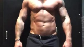 Fit tattooed man strips in gym locker room