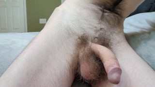 Hairy guy playing with his big cock on the edge of bed