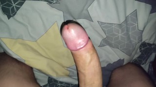 A young and slender guy jerks off his big dick in bed before going to bed and cums...