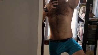 Hairy tattooed guy strips, licks biceps, strokes cock