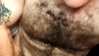 Hairy tattooed guy jerks off big cock and eats cum