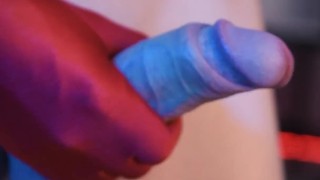 A man in a white shirt masturbates his penis in red gloves