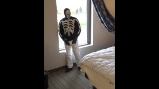 skeleton mask in pantyhose and jeans at hotel window