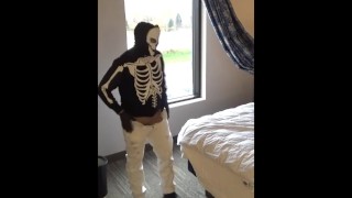 skeleton mask in pantyhose and jeans at hotel window
